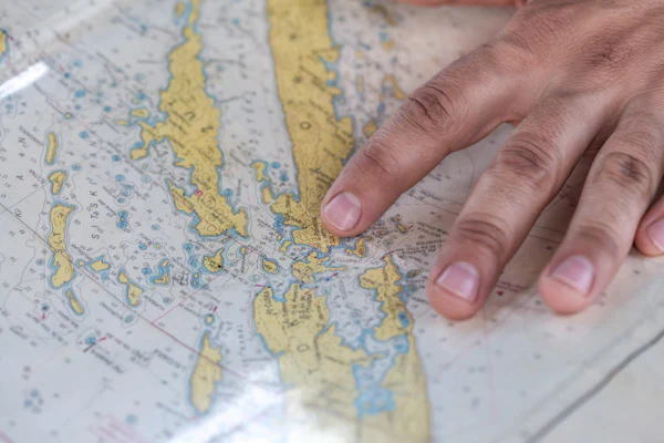 Mano señalando una ruta sobre una carta náutica
