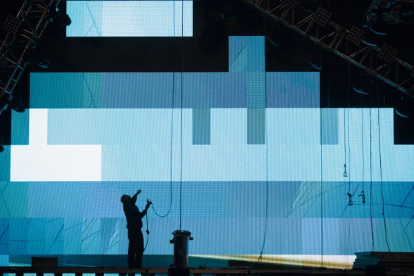 Técnico de espaldas instalando una pantalla LED de gran formato en un escenario